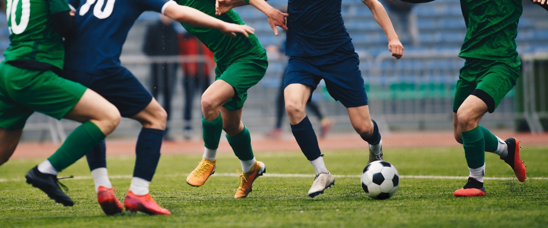 Soccer football player dribbling a ball and kick a ball during match in the stadium. Footballers in action on the tournament game. Adult football competition