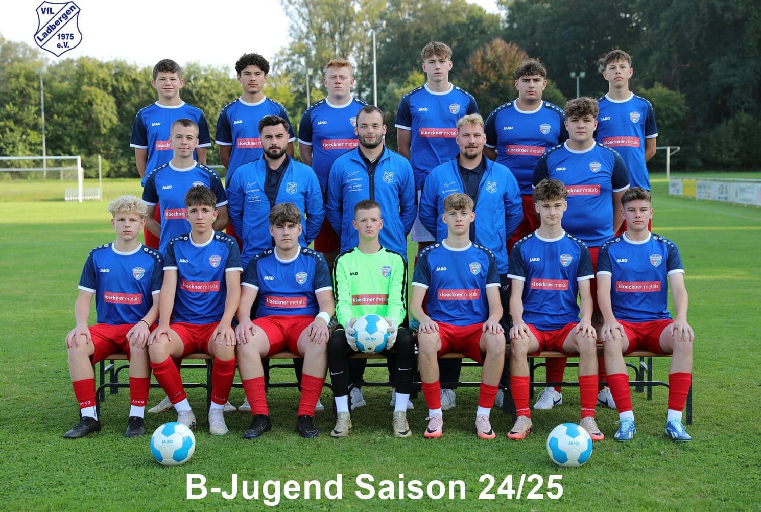 Ein Fußballteam posiert auf einem Spielfeld. Spieler tragen blaue Trikots. 